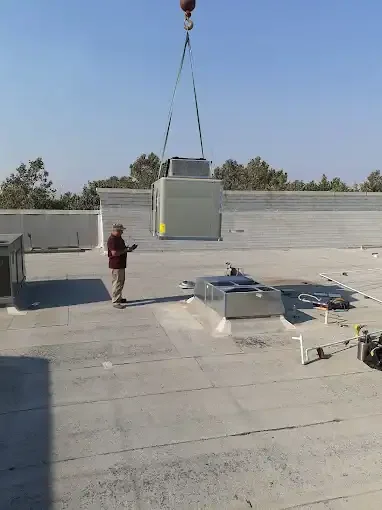 Rooftop HVAC unit being lifted by crane onto commercial flat roof installation