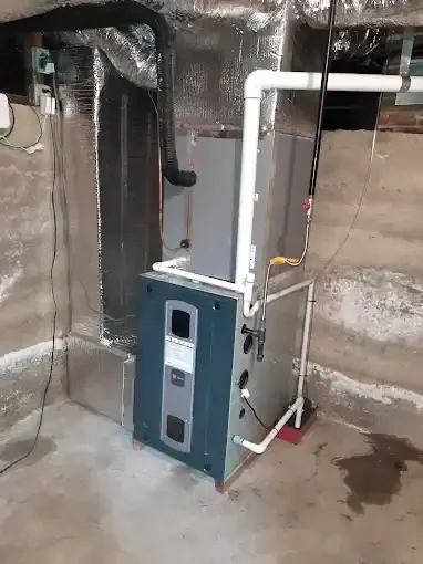Teal and white furnace unit with wrapped ductwork and white PVC piping in basement installation